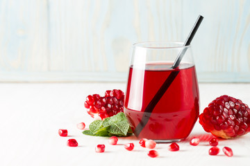 A glass of pomegranate juice with fresh pomegranate fruits on wooden table. Vitamins and minerals. Healthy drink concept.