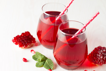 A glass of pomegranate juice with fresh pomegranate fruits on wooden table. Vitamins and minerals. Healthy drink concept.