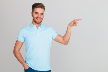 smiling relaxed man wearing blue polo t-shirt pointing to side