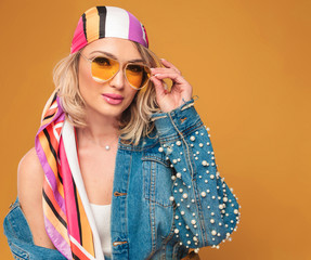 sensual blonde woman with colored headscarf fixing her yellow sunglasses