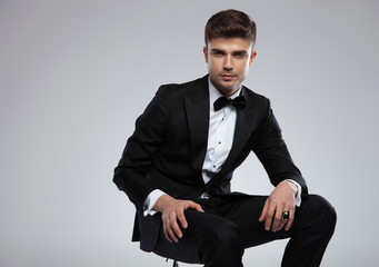 portrait of seductive stylish man in tuxedo siting