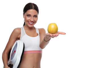 fit woman holding a scale offers you an apple