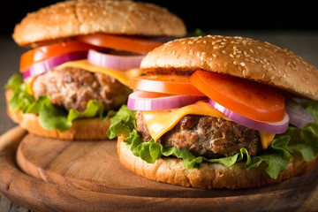 Close-up photo of home made hamburger with beer made of beef, onion, tomato, lettuce, cheese and spices. Fresh burger closeup on wooden rustic table with potato fries and chips.