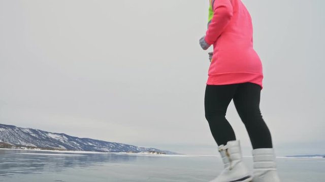 Woman on ice in winter is do sport in athletic race walking. Girl is training in winter on ice. Sports nordic power walking athlete prepares for sport competition exposure. Athlete in sports exercise
