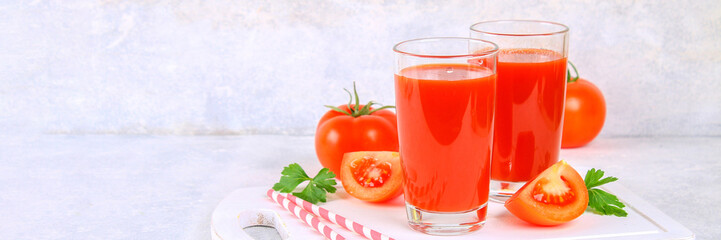 Tomato juice in glasses on a gray concrete table.