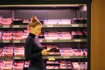 Woman purchasing a packet of meat at the supermarket 