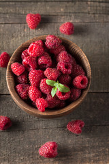 Ripe fresh sweet raspberries in a wooden bowl on wooden table background.