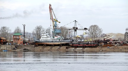 Fototapeta na wymiar Maintenance ships / IRKUTSK, RUSSIA - April 11, 2018: Viewed to cargo shipyard of Irkutsk city along Angara river, Siberian area. Lots of ships park for maintenance and transferring