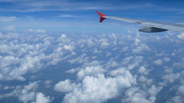 4K footage. traveling by air. aerial view through an airplane window. wing airplane and beautiful white clouds in blue sky for background