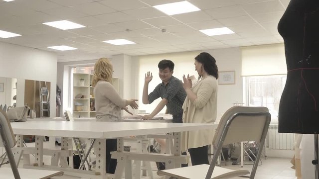 A team of designers creates clothes in the sewing studio. team high five