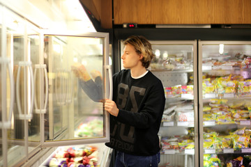Man shopping in supermarket, reading product information