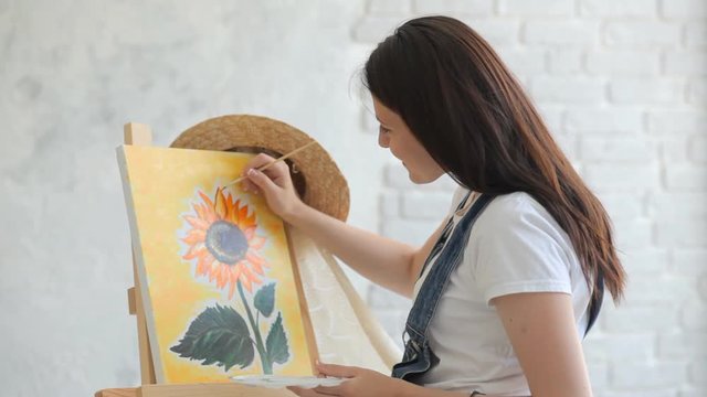 Getting creative. Woman artist painting a sunflower at home