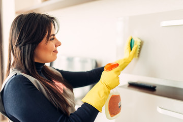 Housemaid cleans furniture with a cleaning spray