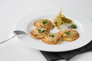 Vegeterian hash brown with pickles and dill on white plate.