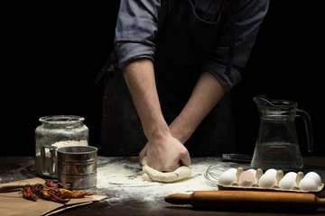 Fototapeta na wymiar Hands are mixing a dough on wooden table
