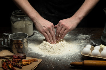 Hands are preparing a dough on wooden table