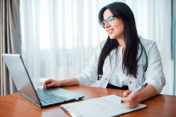 Family doctor concept, specialist sits at laptop