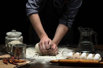 Hands are kneading the dough on wooden table