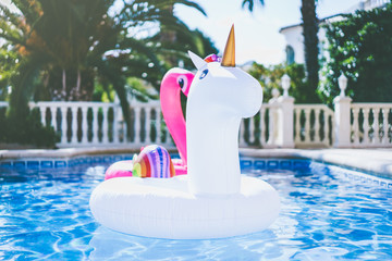 Inflatable colorful white unicorn and pink flamingo at the swimming pool. Fun time in the Summer at swimming pool. concept