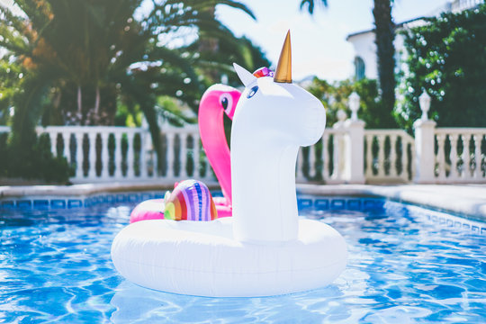 Inflatable colorful white unicorn and pink flamingo at the swimming pool. Fun time in the Summer at swimming pool. concept