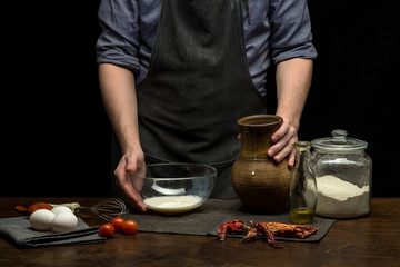 Chef hands are preparing dough on the table. black background