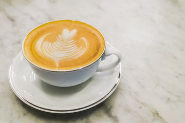 Cup of hot latte art coffee on marble table