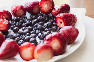 Strawberries and blueberry on the white plate, high angle view