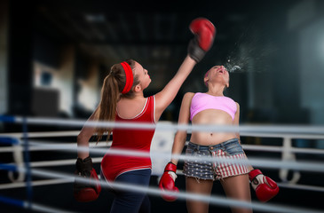 Two female kickboxers fights on the ring, low kick