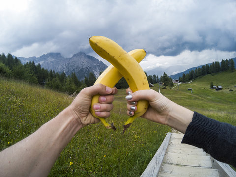 Tourists take a rest and eating babanas with a view on landscape of Dolomites moutains and a gree forest on a background. South Tyrol, Italy, Alp. Captured on action camera.