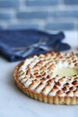 lemon meringue pie served on ceramic plate presented on a white Carrera marble counter with grey bricks background