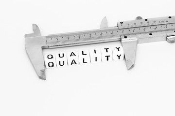 Quality symbol with alphabet cubes and caliper