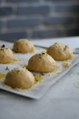 unbaked buns with olive oil rosemary and salt on a tray covered with baking paper on white marble counter