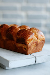 freshly baked challah bread on a wooden white serving board on a white counter