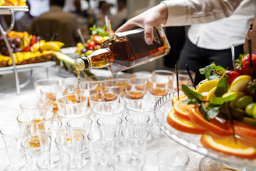 Barman pouring whiskey in crystal glasses
