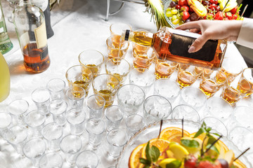 Close up of barman hands pouring whiskey in crystal glasses