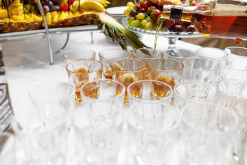 Close up of barman hands pouring whiskey in crystal glasses