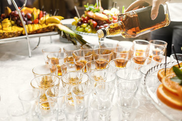 Close up of barman hands pouring whiskey in crystal glasses