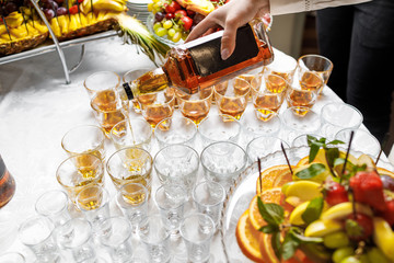 Barman pouring whiskey in crystal glasses