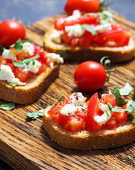 Italian bruschetta close-up with cherry tomatoes and cheese on crispy toast.