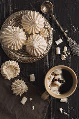 Meringue and coffee with marshmallow on a dark rustic background. The view from above, flat lay.