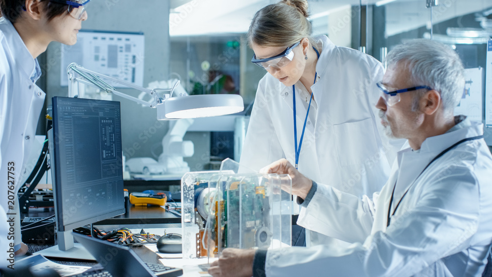 Wall mural team of scientists choose between printed circuit board to work with. in the background technologica