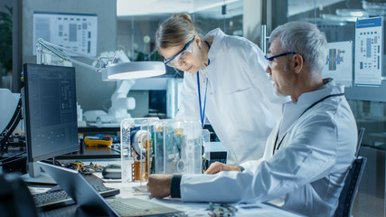 Two Computer Scientists Choose Between Printed Circuit Board to Work With. In The Background...