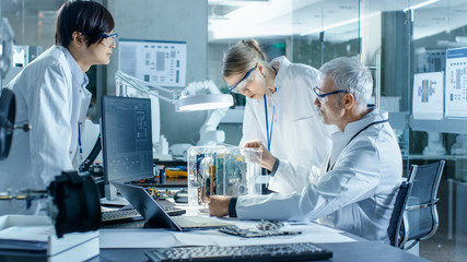 Team of Scientists Choose Between Printed Circuit Board to Work With. In The Background Technologically Advanced Scientific Research Center.