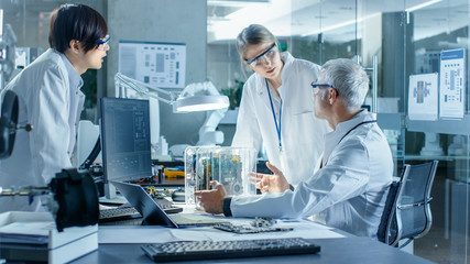 Team of Scientists Choose Between Printed Circuit Board to Work With. In The Background...