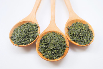 Dried green tea in a wooden spoon