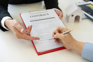 Businessman hands are pointing at the line needs autograph and man signing contract with home...