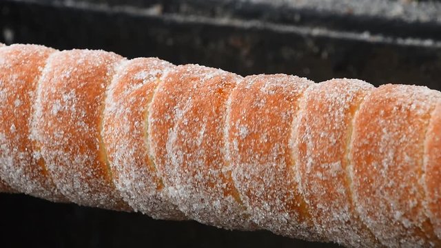 Close up sweet Trdelnik baking on grill and rolling, this spit cake is popular in Europe, Austria, Hungary, Slovakia and Czech, especially in Prague