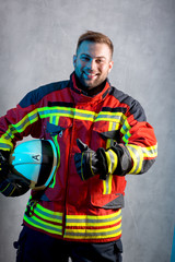 Feuerwehr Truppmann, stehend vor Betonwand,Helm unterm Arm lacht in die Kamera, Daumen hoch