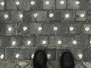 Feet standing on tactile paving steel studs