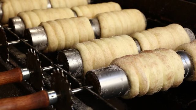 Close up sweet Trdelnik baking on grill and rolling, this spit cake is popular in Europe, Austria, Hungary, Slovakia and Czech, especially in Prague
